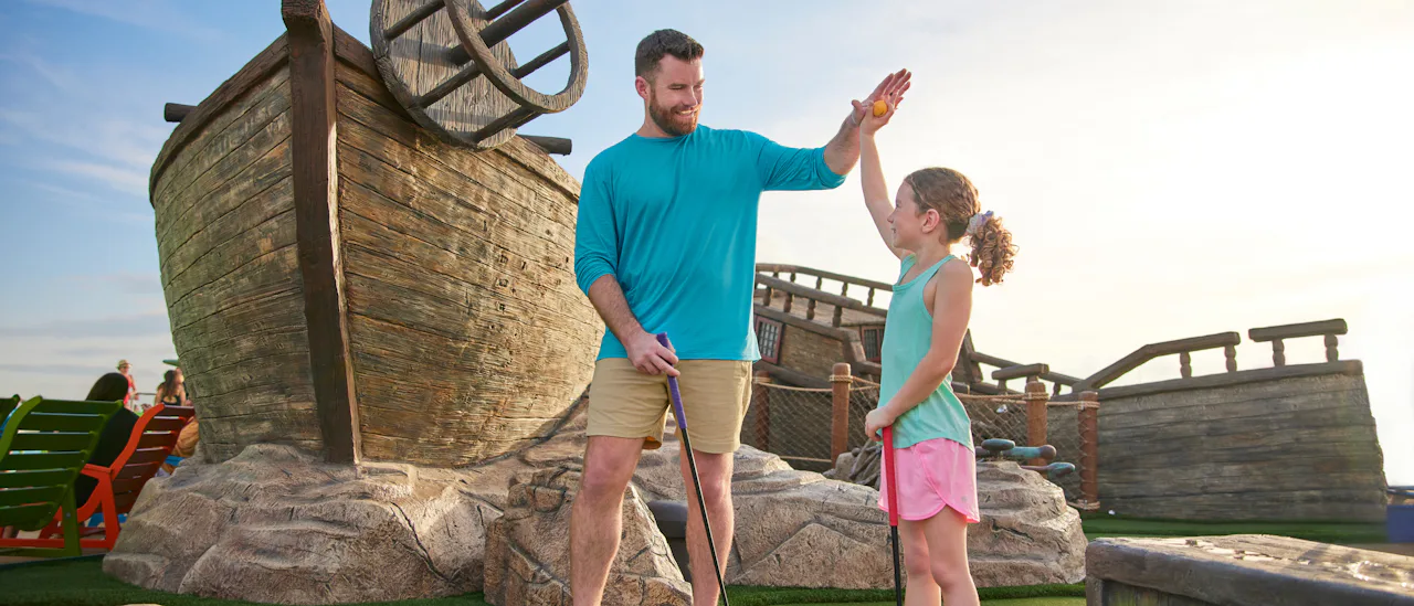 Father and daughter share a high-five playing mini-golf