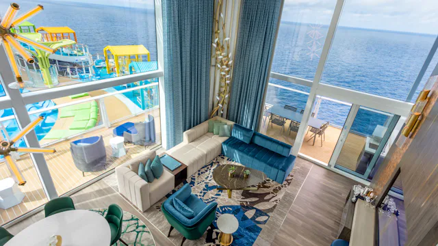 An in-suite dining area with a view out through tall glass windows to a private balcony and seating area