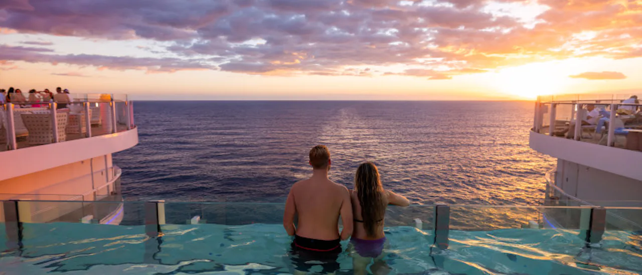 A couple watch the sunset from the adults only infinity pool