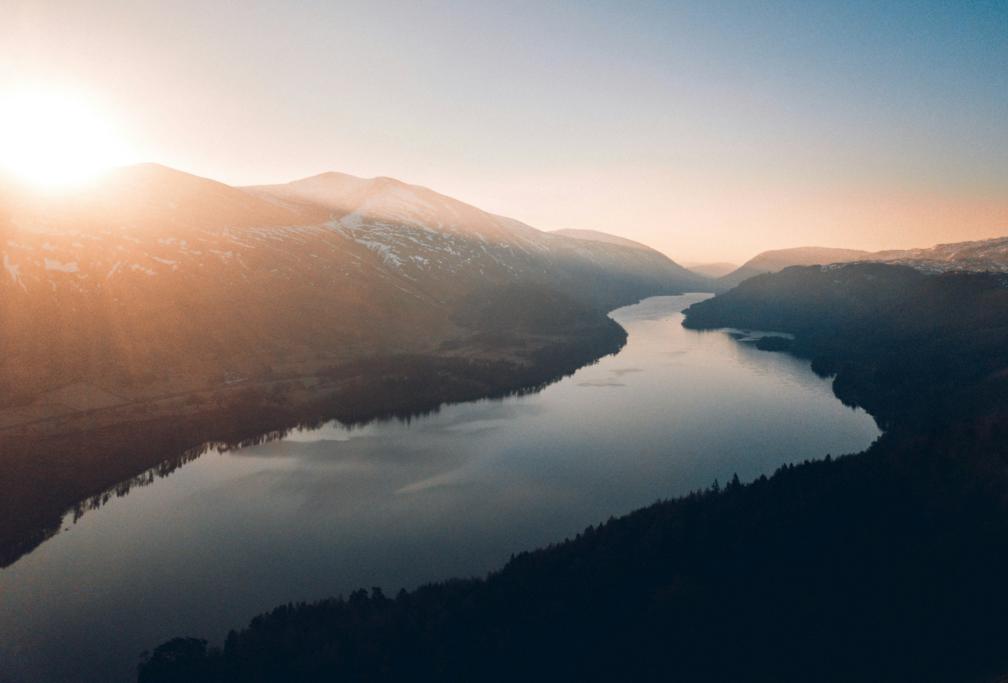 Scenic aerial view of a nile river at sunrise, featuring forested valleys and calm waters reflecting the soft morning light.