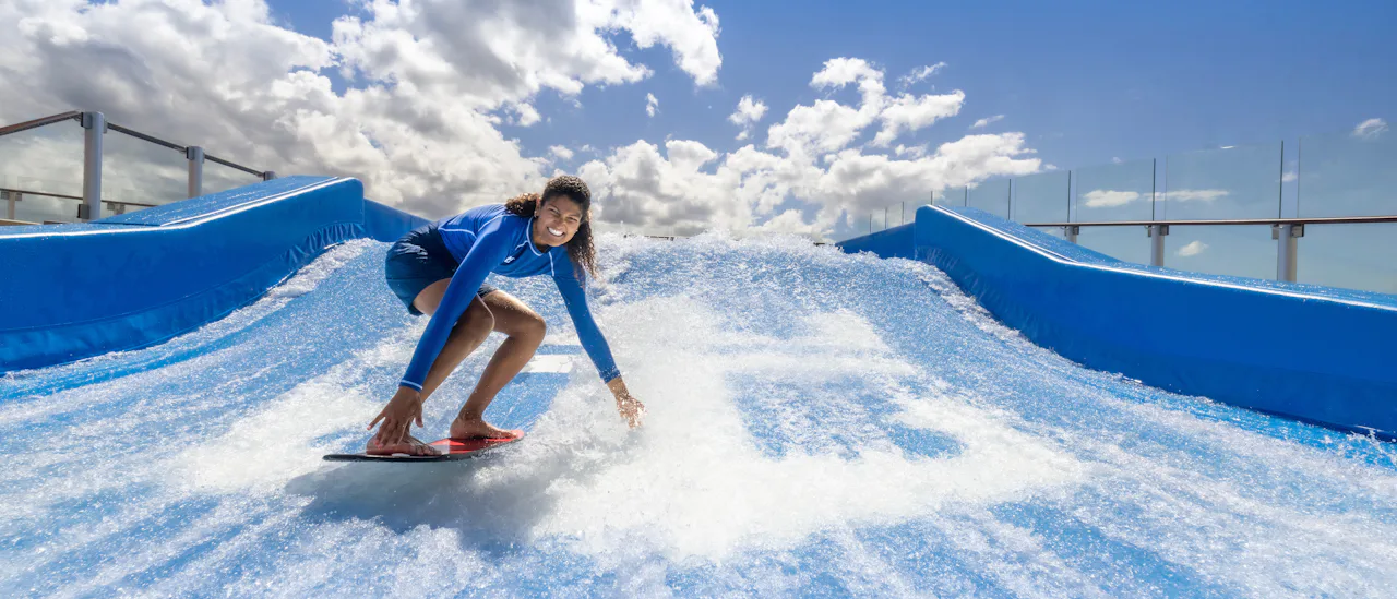 A girl stands on a surfboard riding the surf simulator