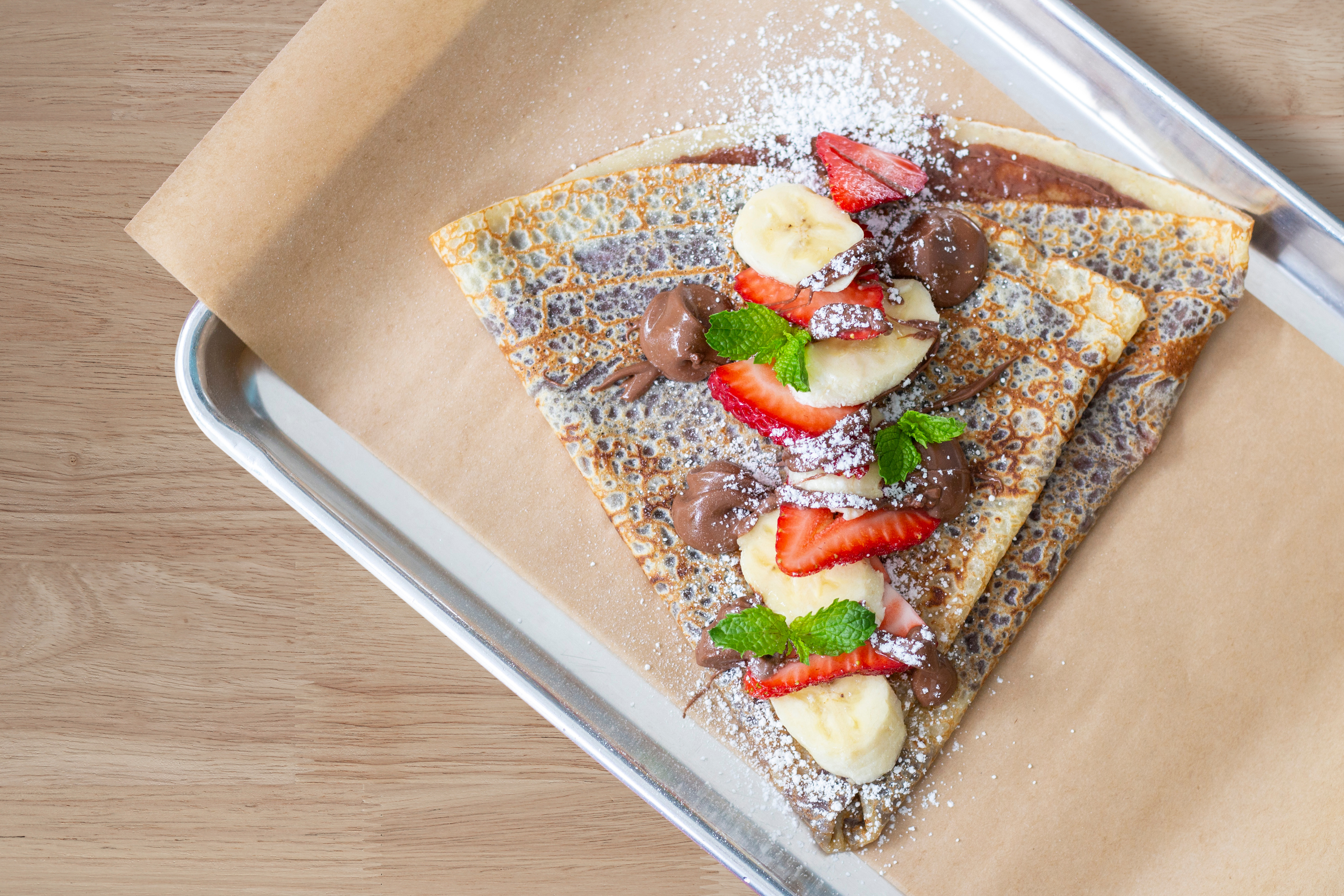A crepe topped with fresh fruit and chocolate
