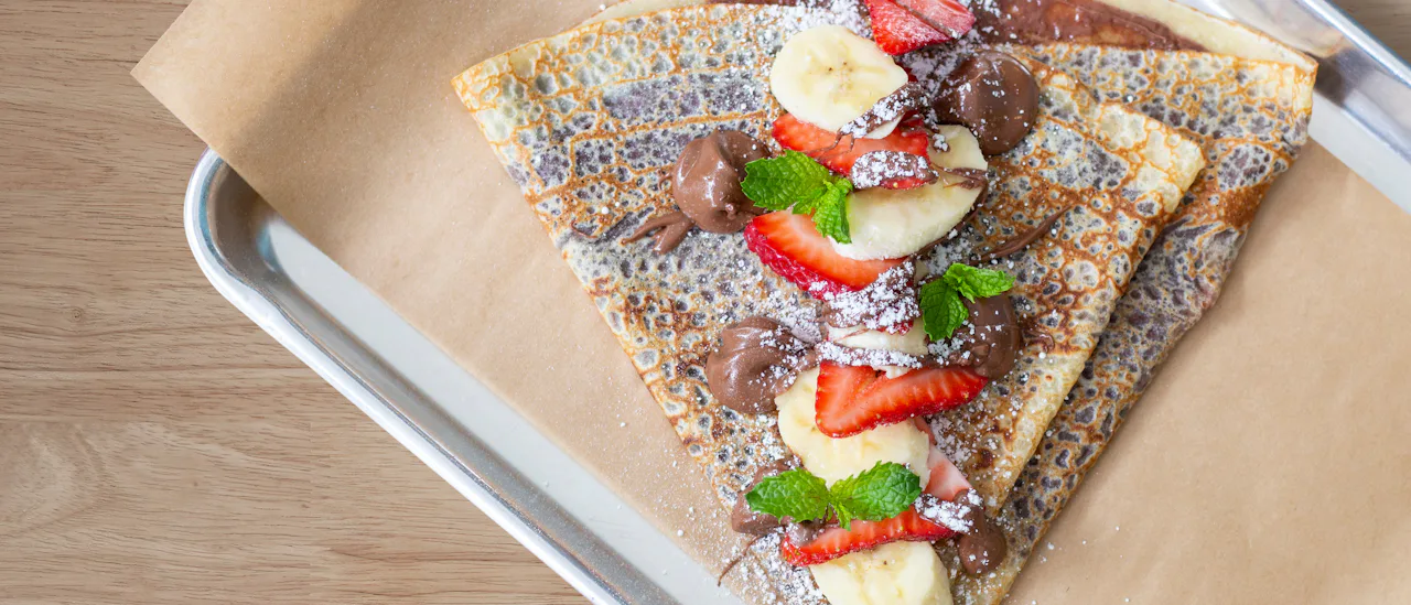 A crepe topped with fresh fruit and chocolate