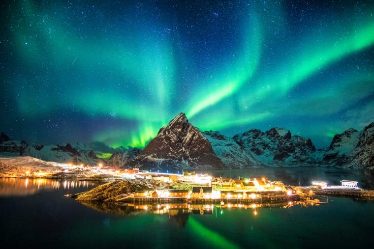 Northern lights cruise - Aurora borealis over mountains in fishing village at Sakrisoy, Lofoten, Norway